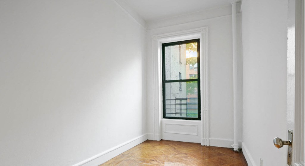 a room with a window and white walls and wood floors