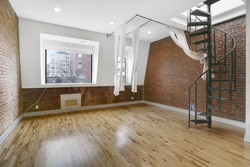 a living room with a spiral staircase and a brick wall