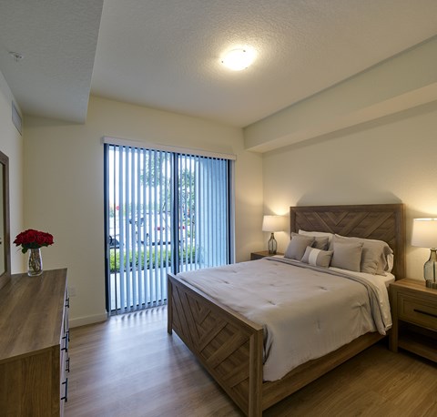 Spacious bedroom at Gateway Luxury Apartments in Pompano Beach, featuring large sliding glass doors that brings in abundant natural light.