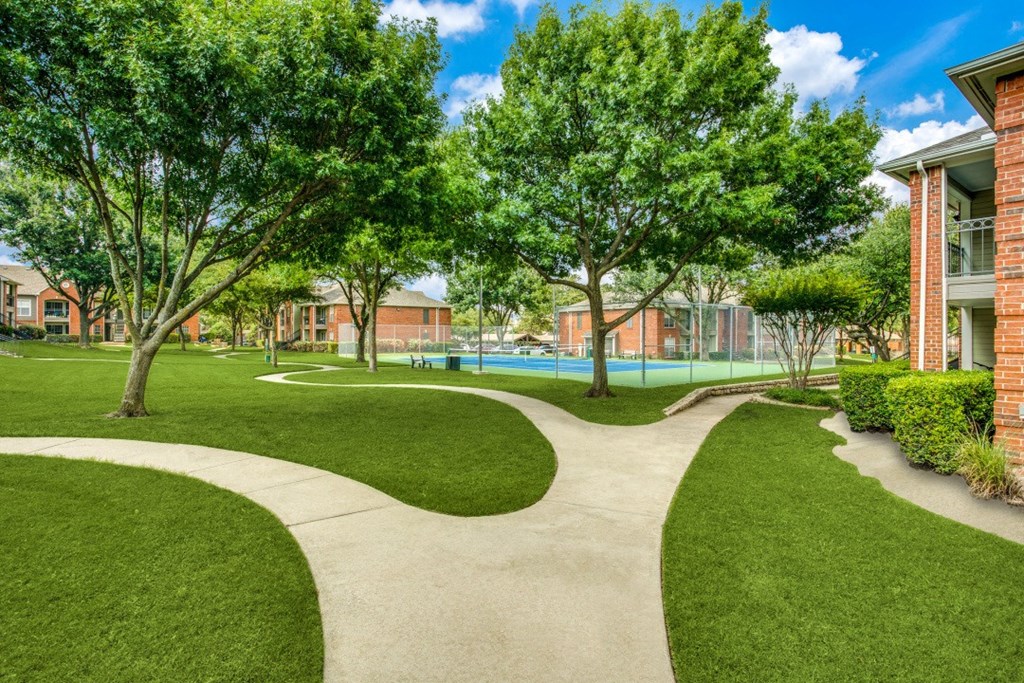 a sidewalk leading to a swimming pool with trees