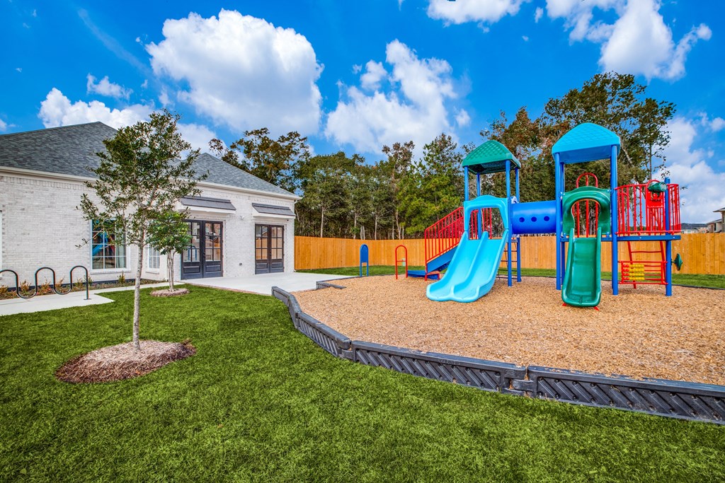 Dog-Friendly Homes for Rent in Humble, TX - Edgewater at the Lagoon - Playground with Slides, Climbing Areas, Woodchips, Well-Maintained Grass, and Surrounding Fence