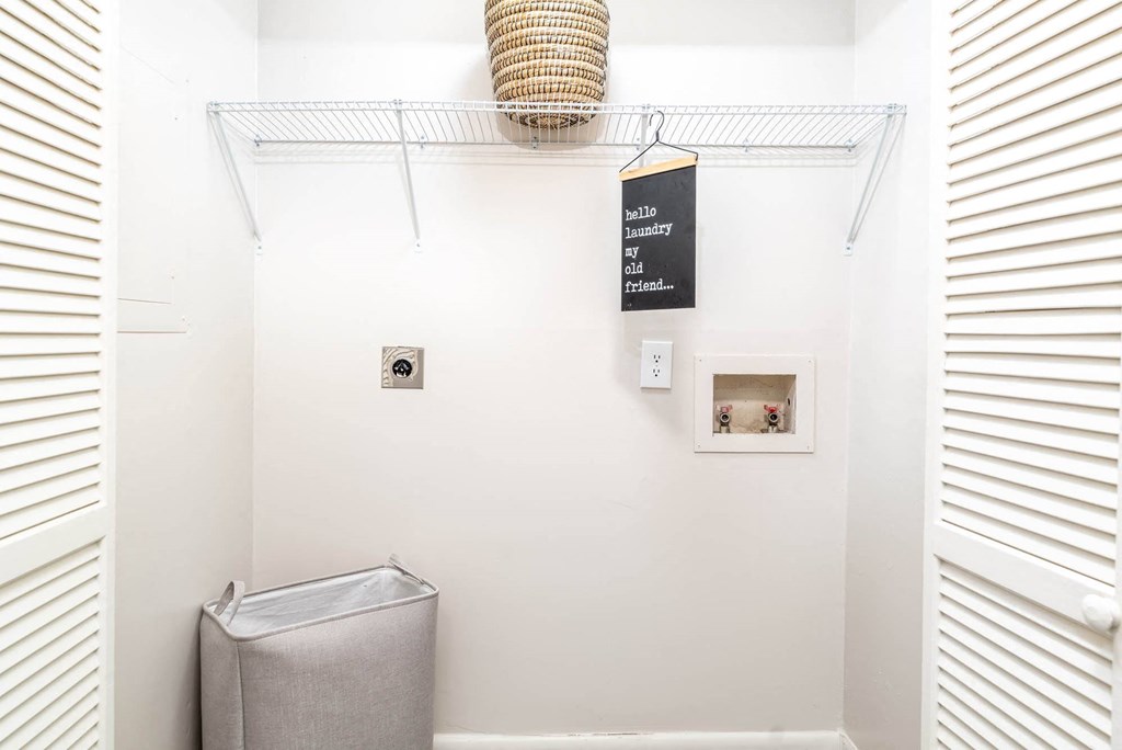 a white bathroom with a trash can and a rack on the wall