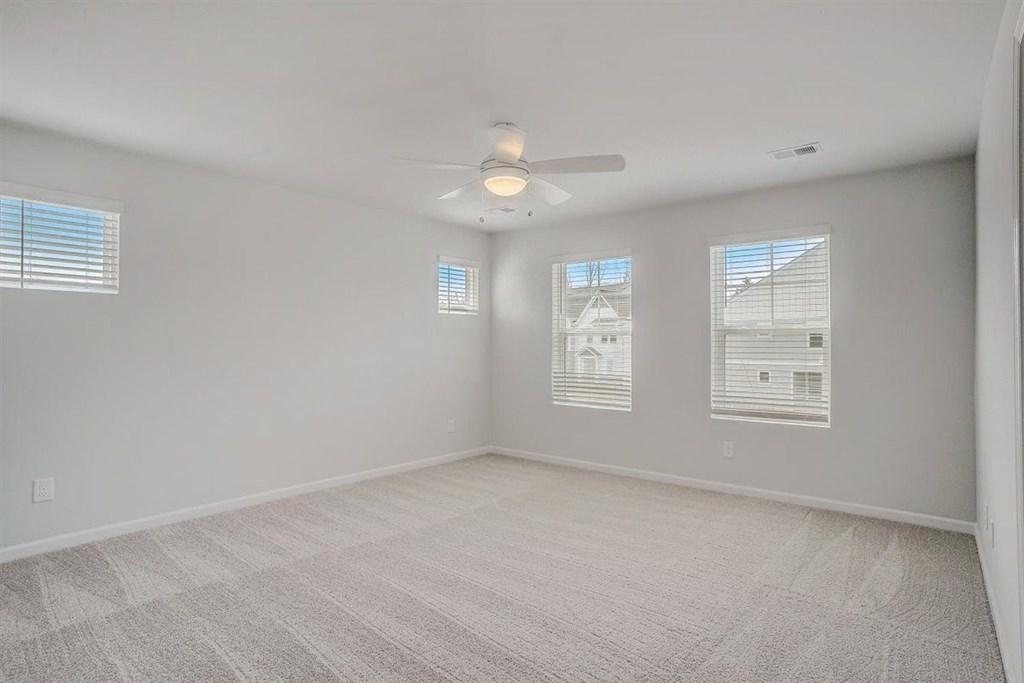 A room with a carpeted floor and a ceiling fan.