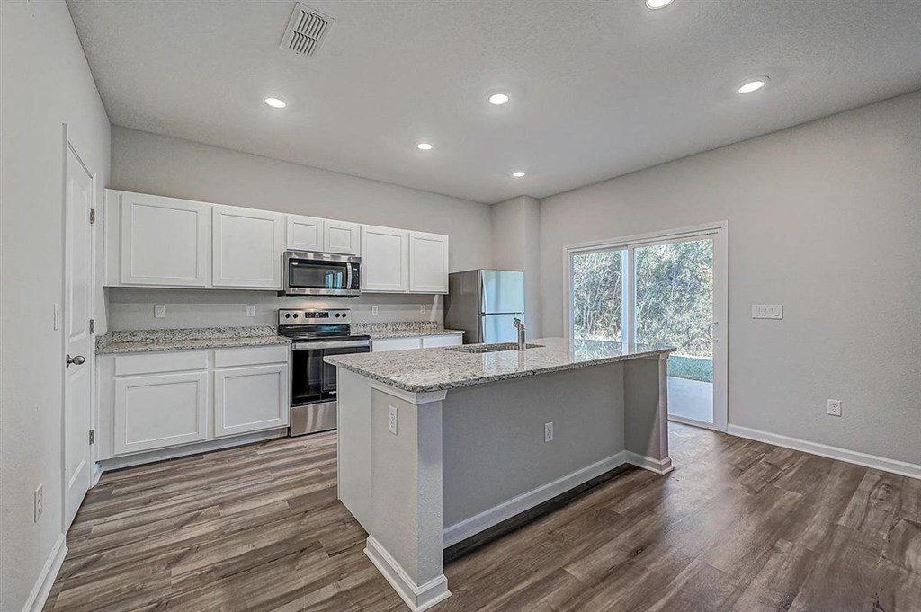 Modern kitchen with white cabinets, granite countertops, stainless steel appliances, and a central island.