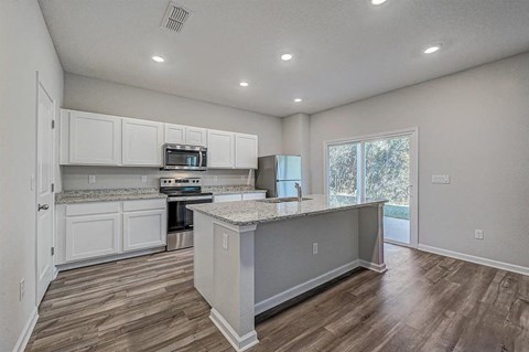 Modern kitchen with white cabinets, granite countertops, stainless steel appliances, and a central island.