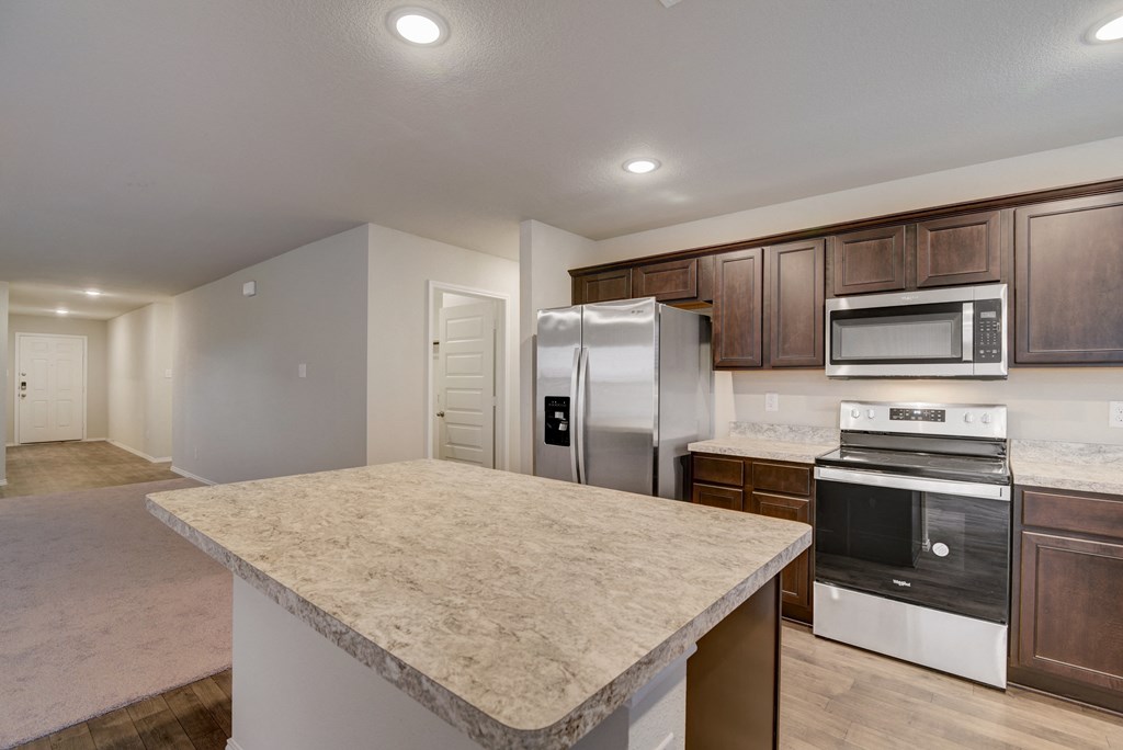 an empty kitchen with an island and stainless steel appliances