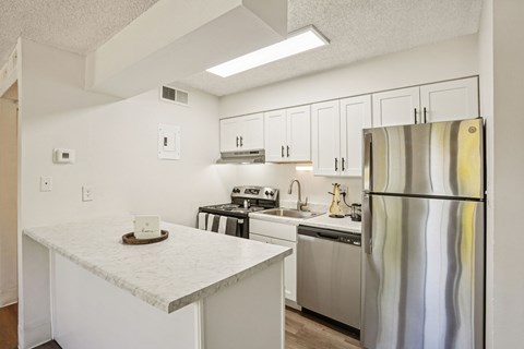 A kitchen with a marble counter top and stainless steel appliances.