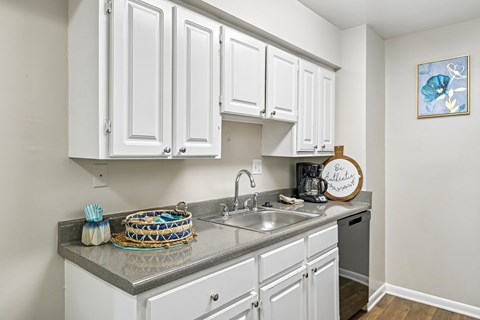 A kitchen with white cabinets and a grey countertop.