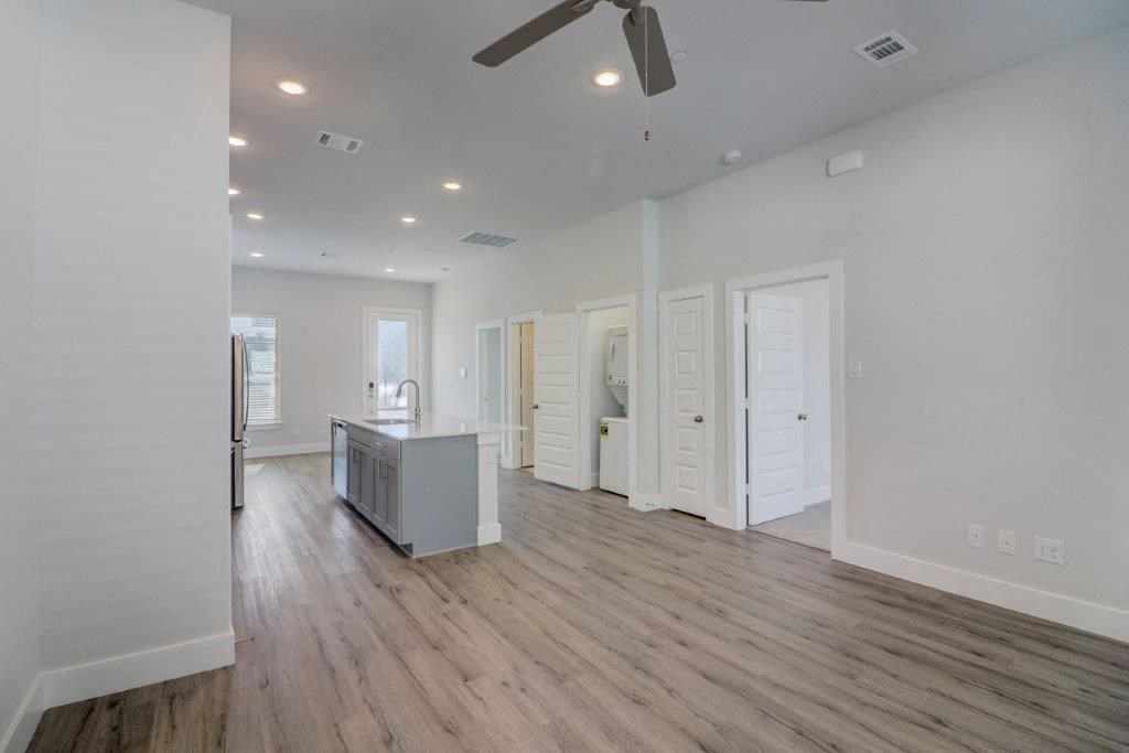 a living room with a kitchen and a ceiling fan