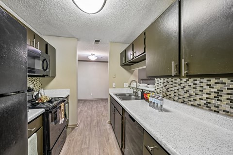 A kitchen with black appliances and a white counter.