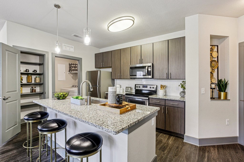 A kitchen with a granite countertop and bar stools.