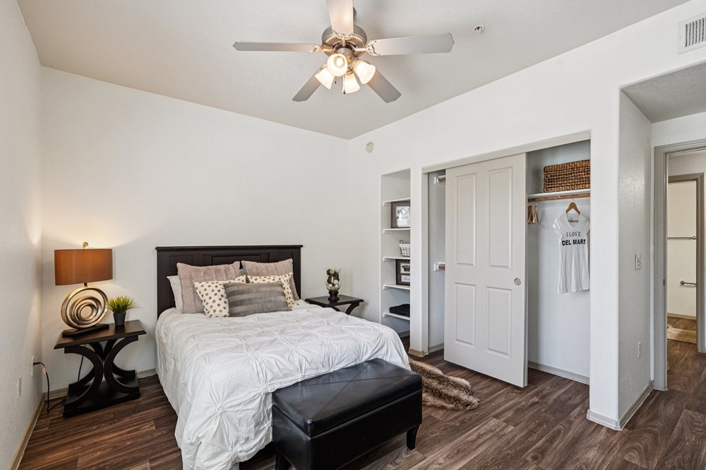 A bedroom with a bed, nightstand, and a ceiling fan.