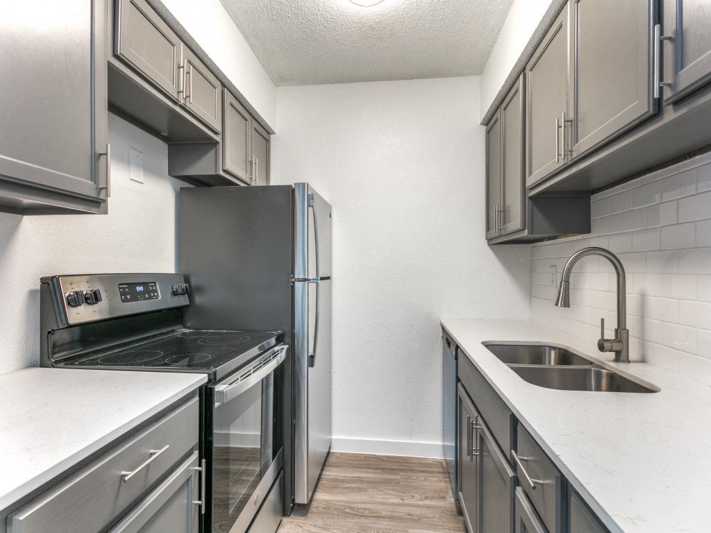 a kitchen with gray cabinets and white countertops