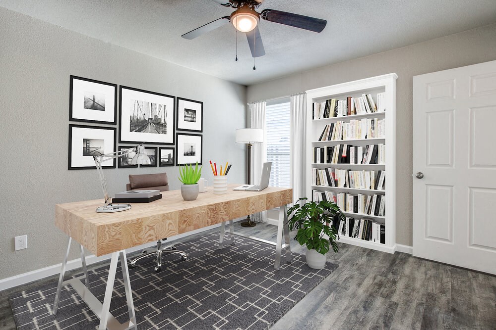 a home office with a ceiling fan and bookshelf