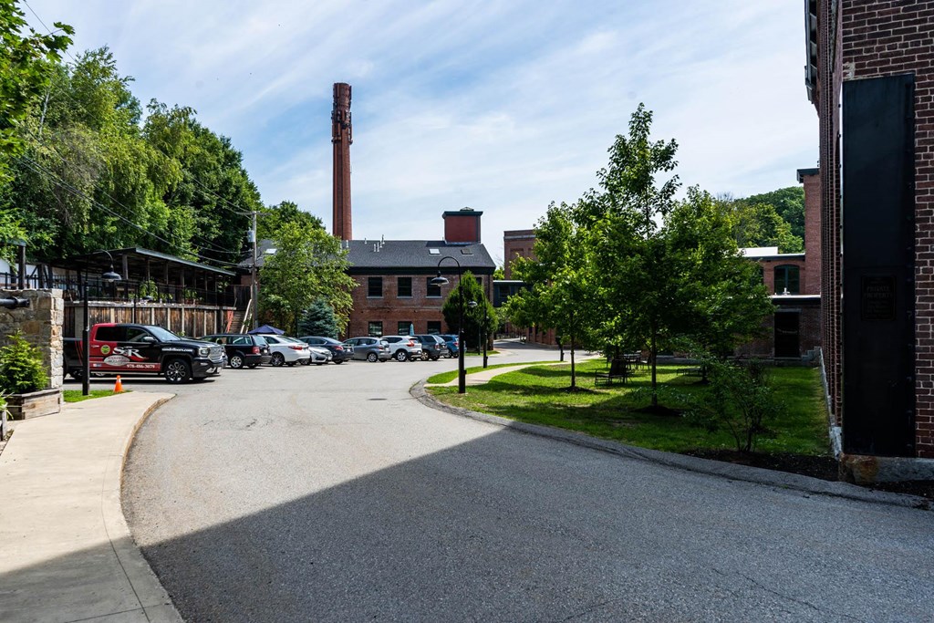 a street in front of a brick building with a smokestack
