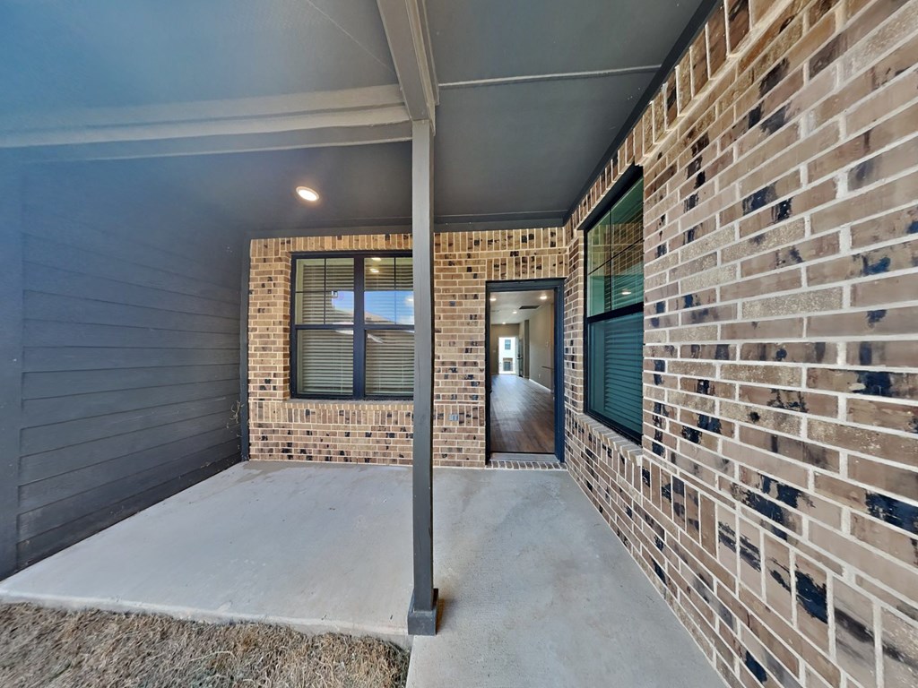 a covered porch with a brick wall and a door to a building