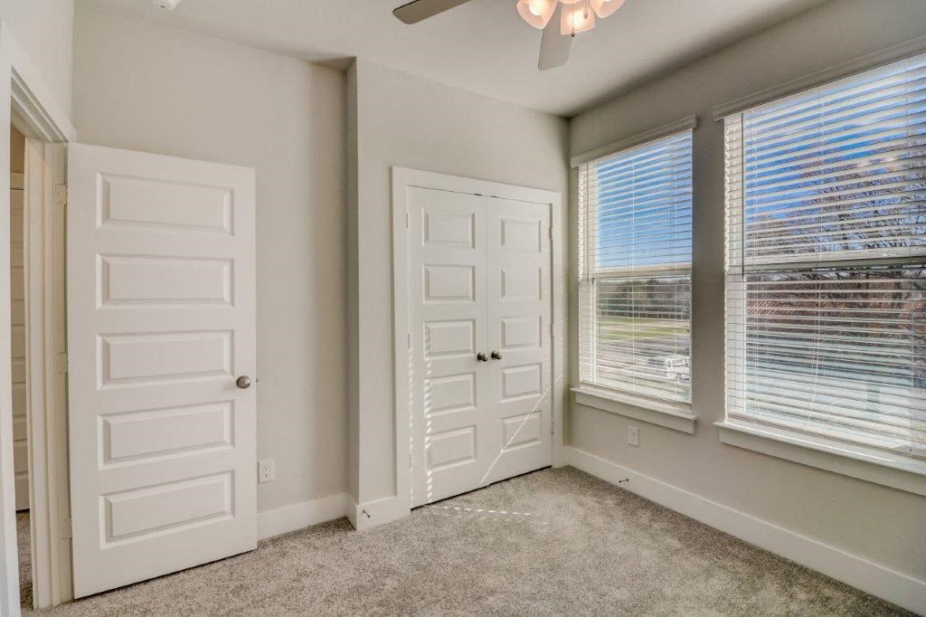 a bedroom with two windows and two doors and a ceiling fan
