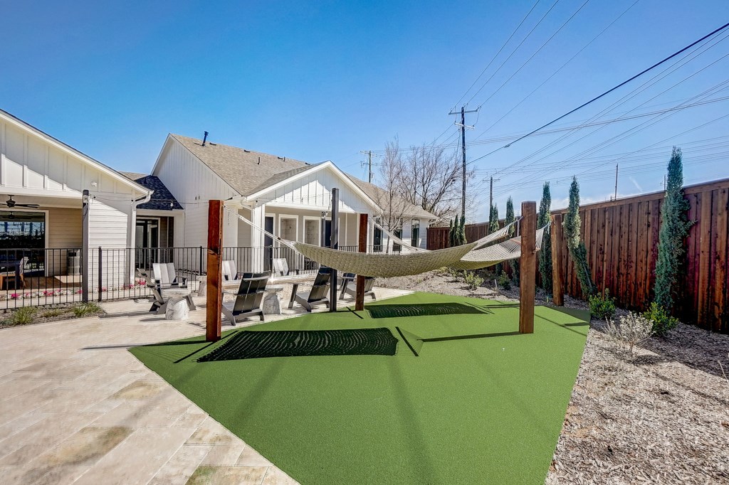 a yard with a hammock on a post in front of a house