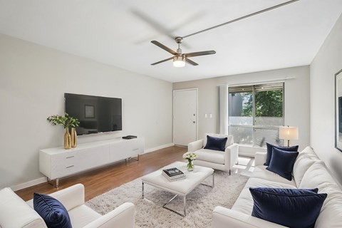 A living room with white furniture and a flat screen TV.