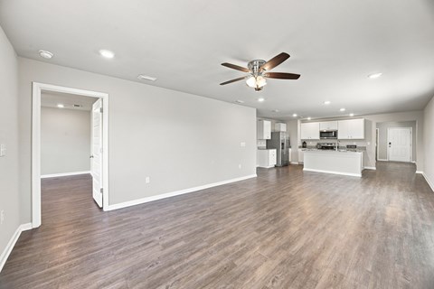 A spacious room with a ceiling fan and hardwood floors.