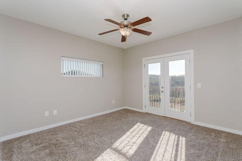 an empty living room with a ceiling fan and a door