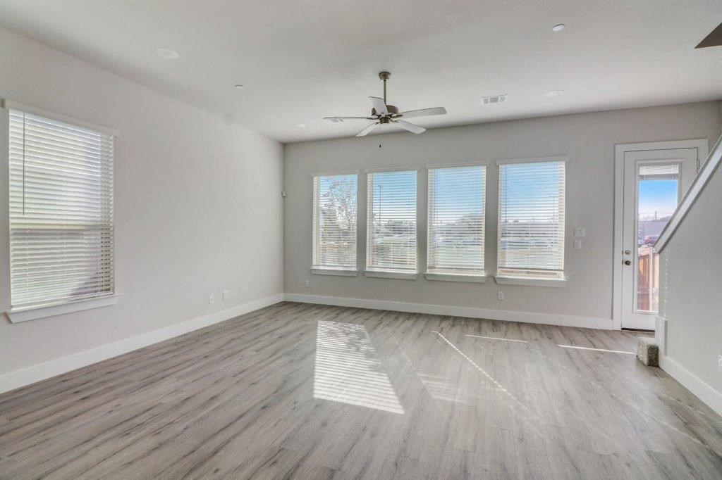 an empty living room with a ceiling fan and windows