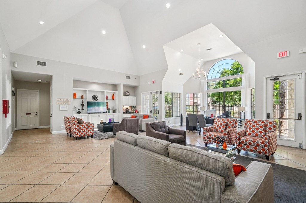 A spacious living room with a grey sofa and a chandelier.