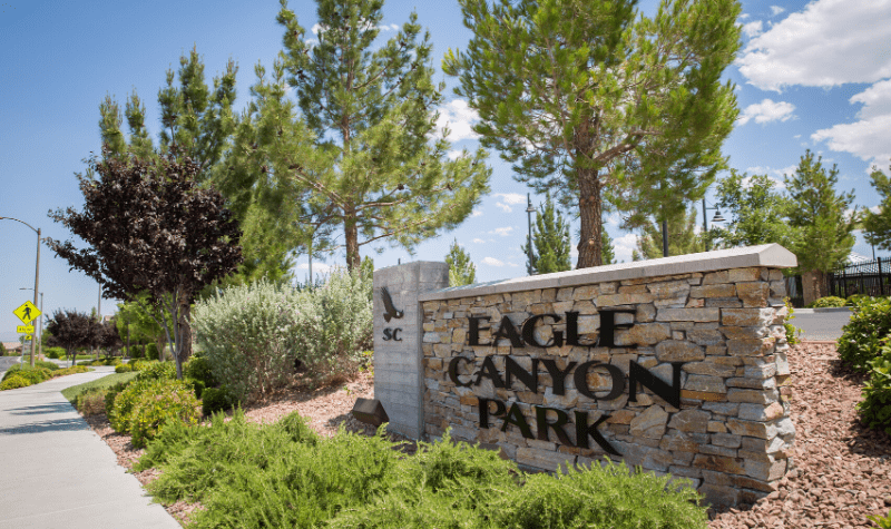 a stone sign that reads eagle canyon park     in front of trees