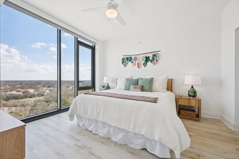 A bedroom with a large bed and a view of the outdoors through the window.