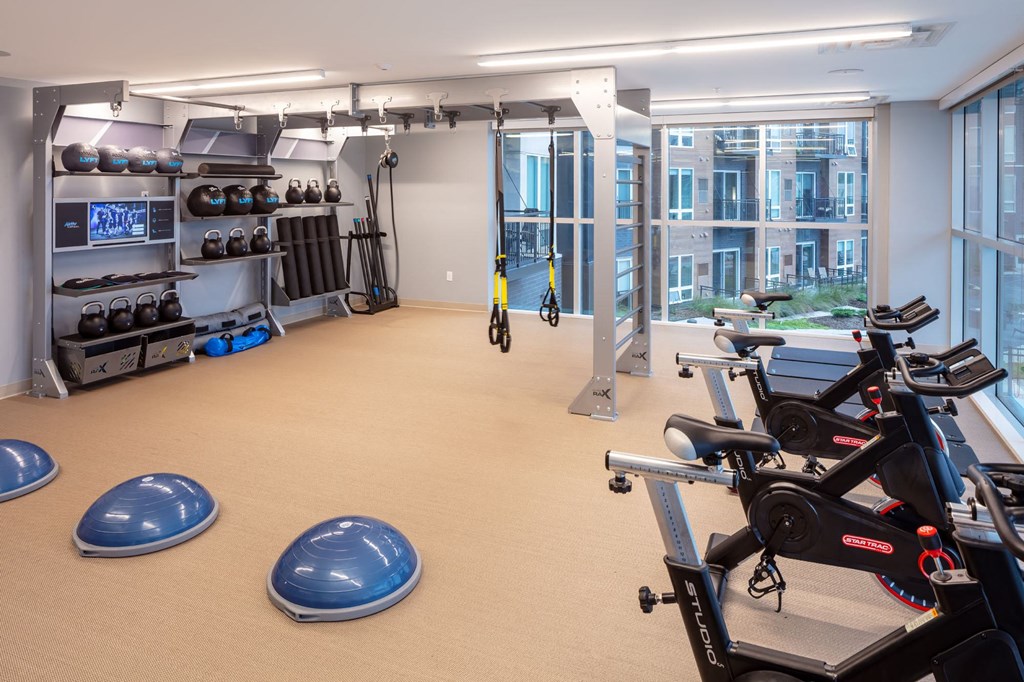 a large fitness room with cardio equipment and a large window