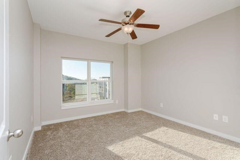 an empty living room with a ceiling fan and a window