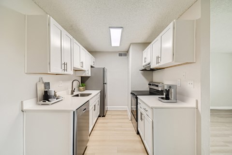 A kitchen with white cabinets and appliances.