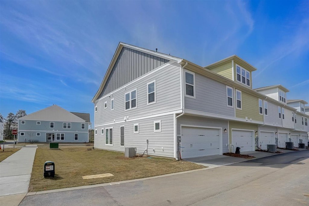A row of houses with garages and a clear blue sky.