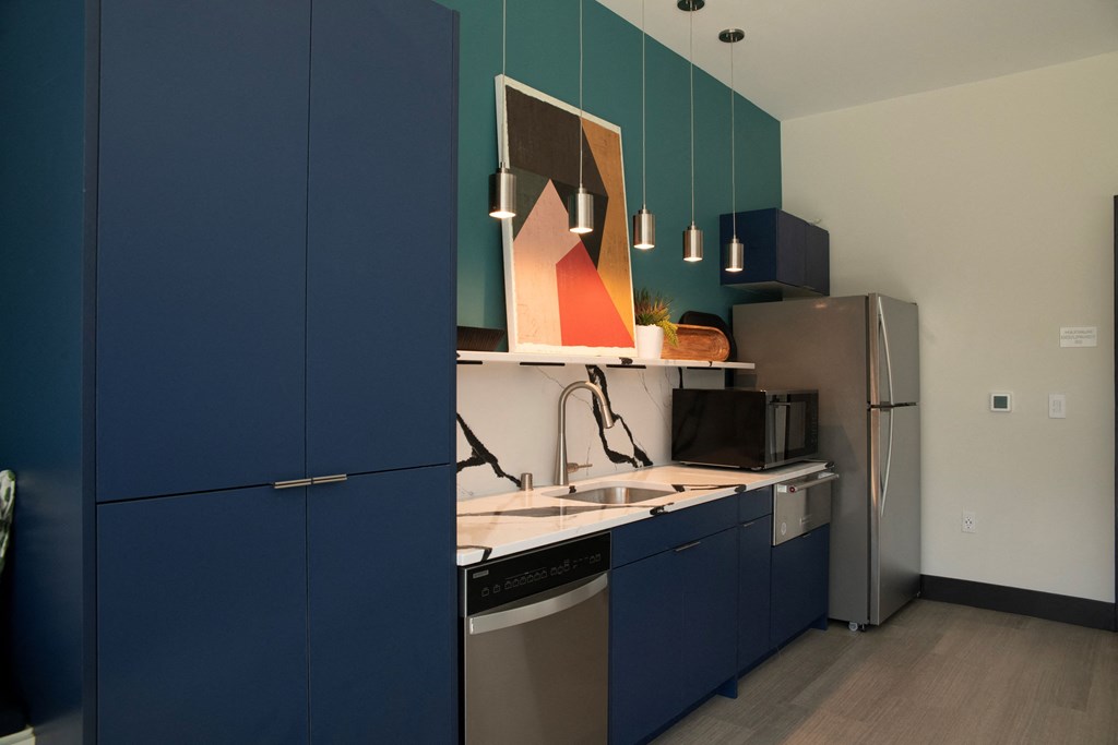 a kitchen with blue cabinets and a stainless steel refrigerator and sink
