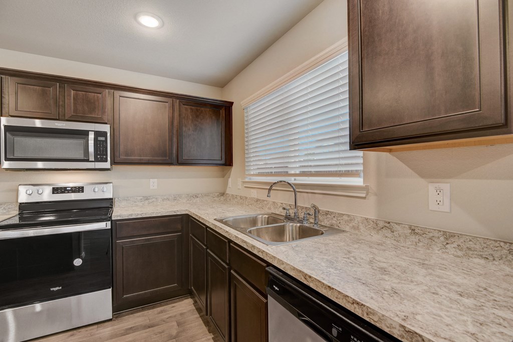 the kitchen of a home with black appliances and marble counter tops