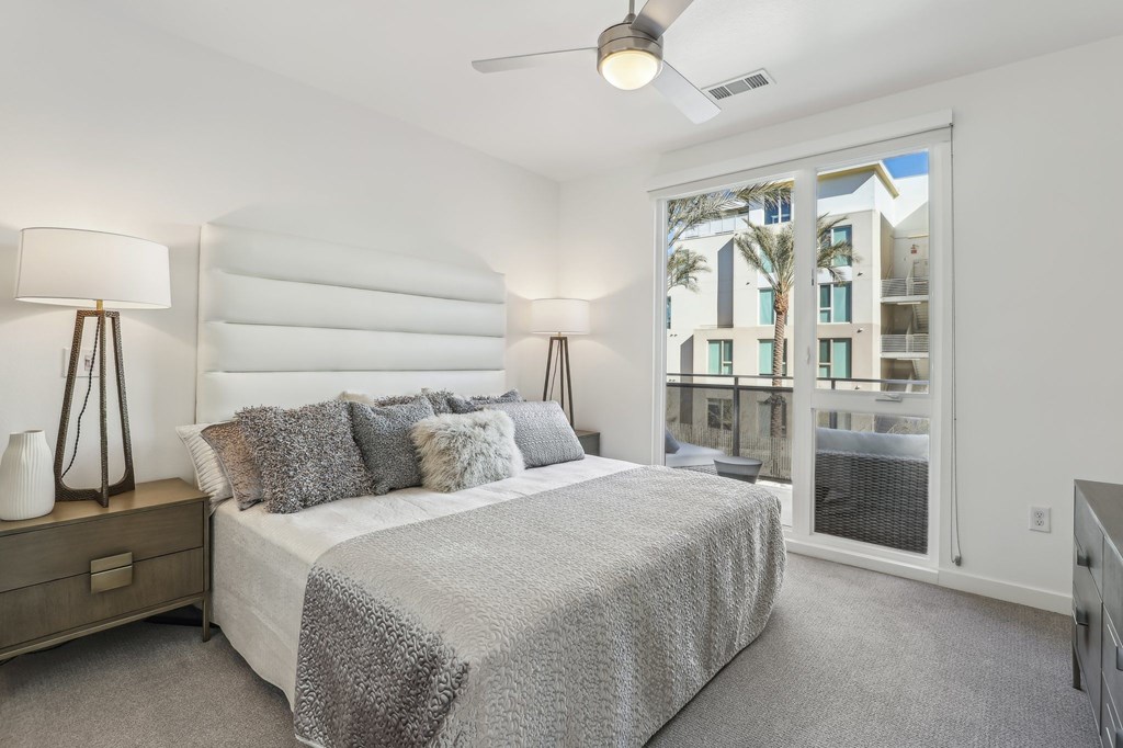 A bedroom with a large bed and a view of a building outside the window.