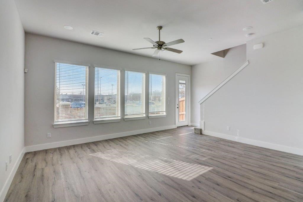 an empty living room with a ceiling fan and windows
