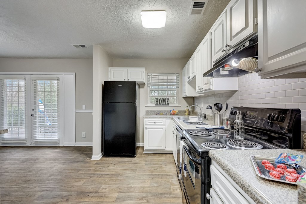 Sandy Springs, GA Apartments – Celebration at Sandy Springs - a kitchen with white cabinets and a black refrigerator