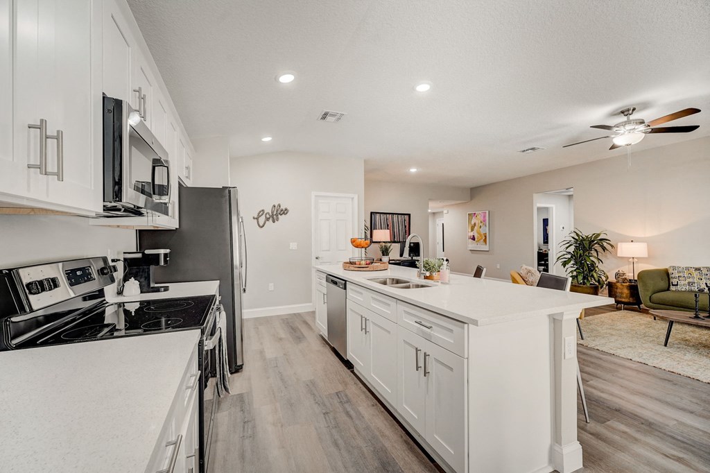 Luxury kitchen with white cabinets and hardwood floors at The Groves at Lake Ella in Lady Lake, Florida, a pet-friendly rental community.