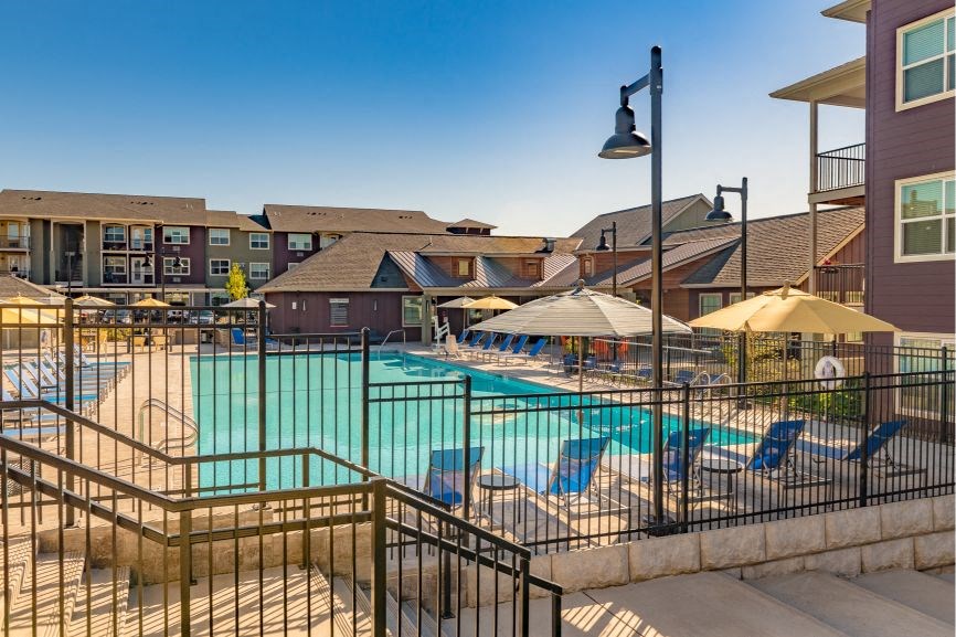 a swimming pool with lounge chairs and umbrellas in front of a building