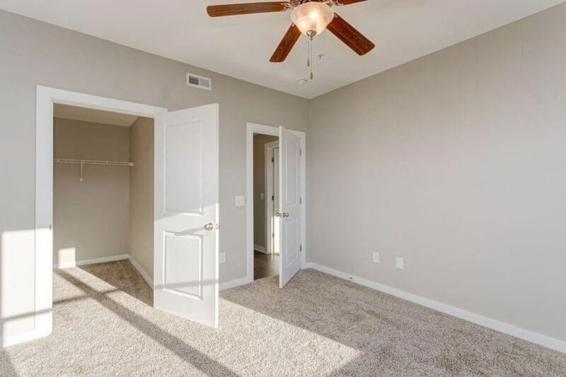an empty bedroom with a ceiling fan and a closet