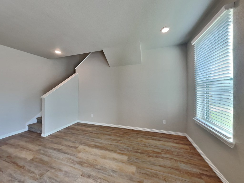 the upstairs bedroom has a large window and hardwood floor
