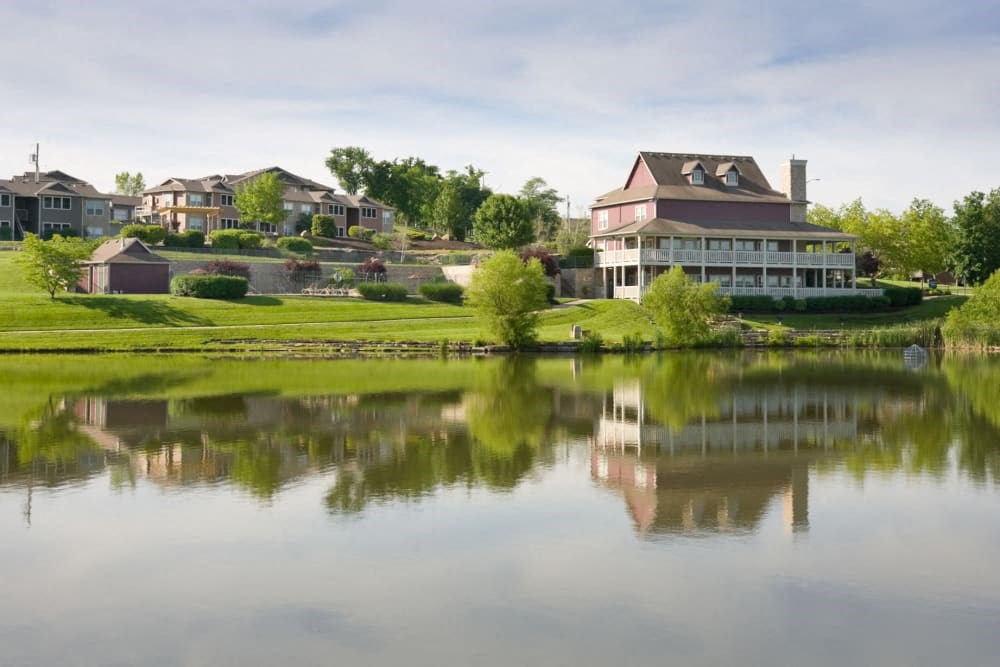 a large pond in front of a large house with a red roof