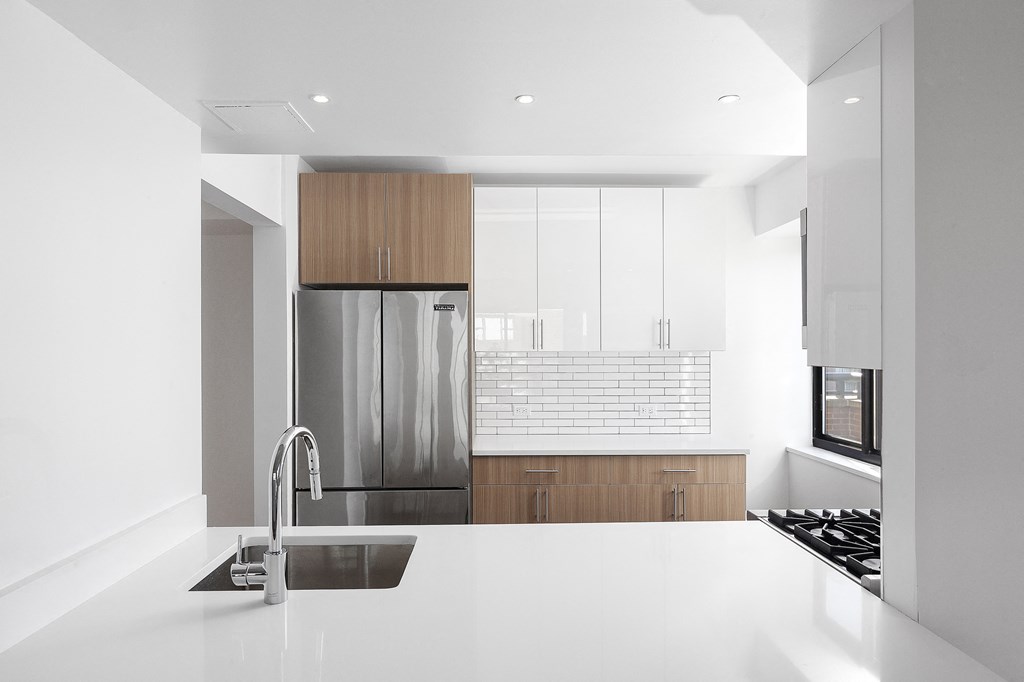a kitchen with white counter tops and a stainless steel refrigerator