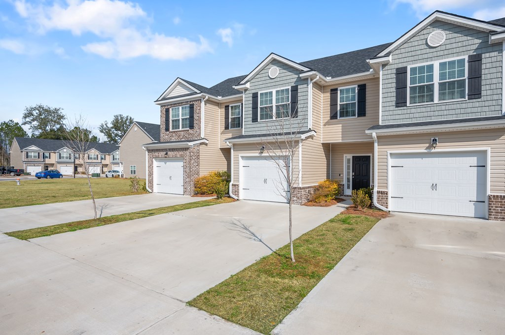 Omnia at Richmond Hill Townhomes in Georgia photo of exterior homes with white doors on a lengthy driveway