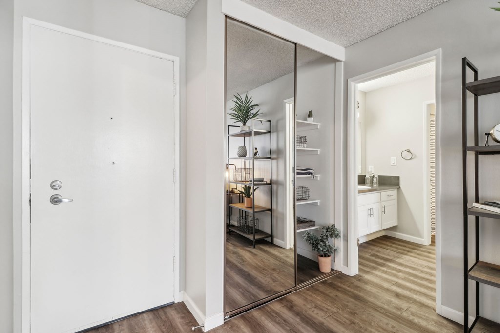 A white door is open to a kitchen and living room.