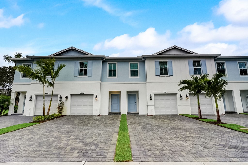 Boatman Hammock Townhomes in Lake Worth, FL photo of  a large white house with palm trees in front of it