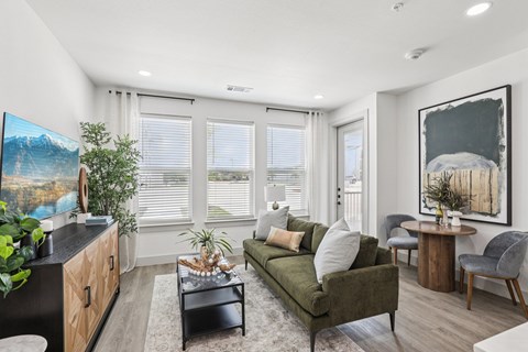 A living room with a green couch, a coffee table, and a painting on the wall.