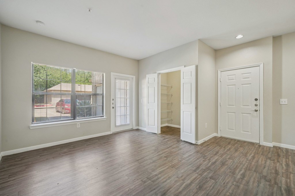 A spacious room with wood flooring and white walls.