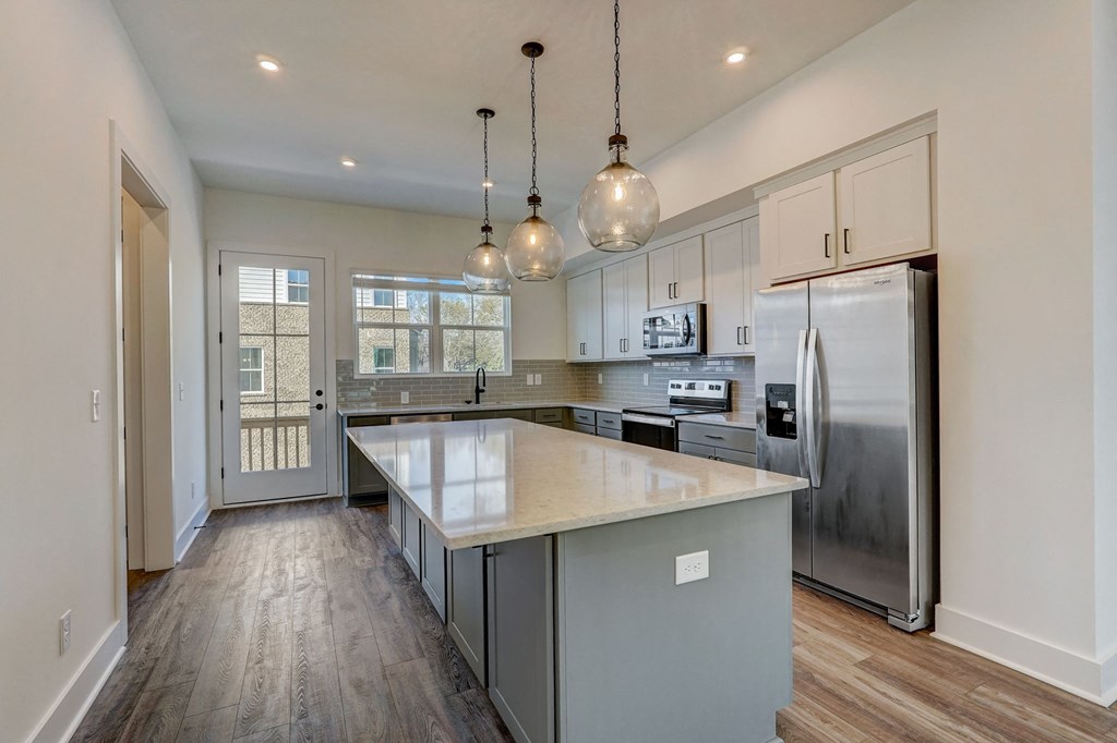 a kitchen with a large island and stainless steel refrigerator